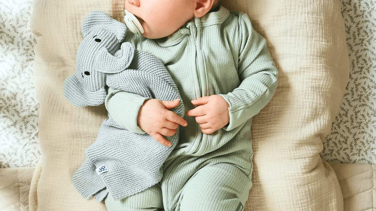 Newborn baby snuggled up wearing the Sage Ribbed Sleepsuit | Bamboo Baby Clothes - GrowGrows