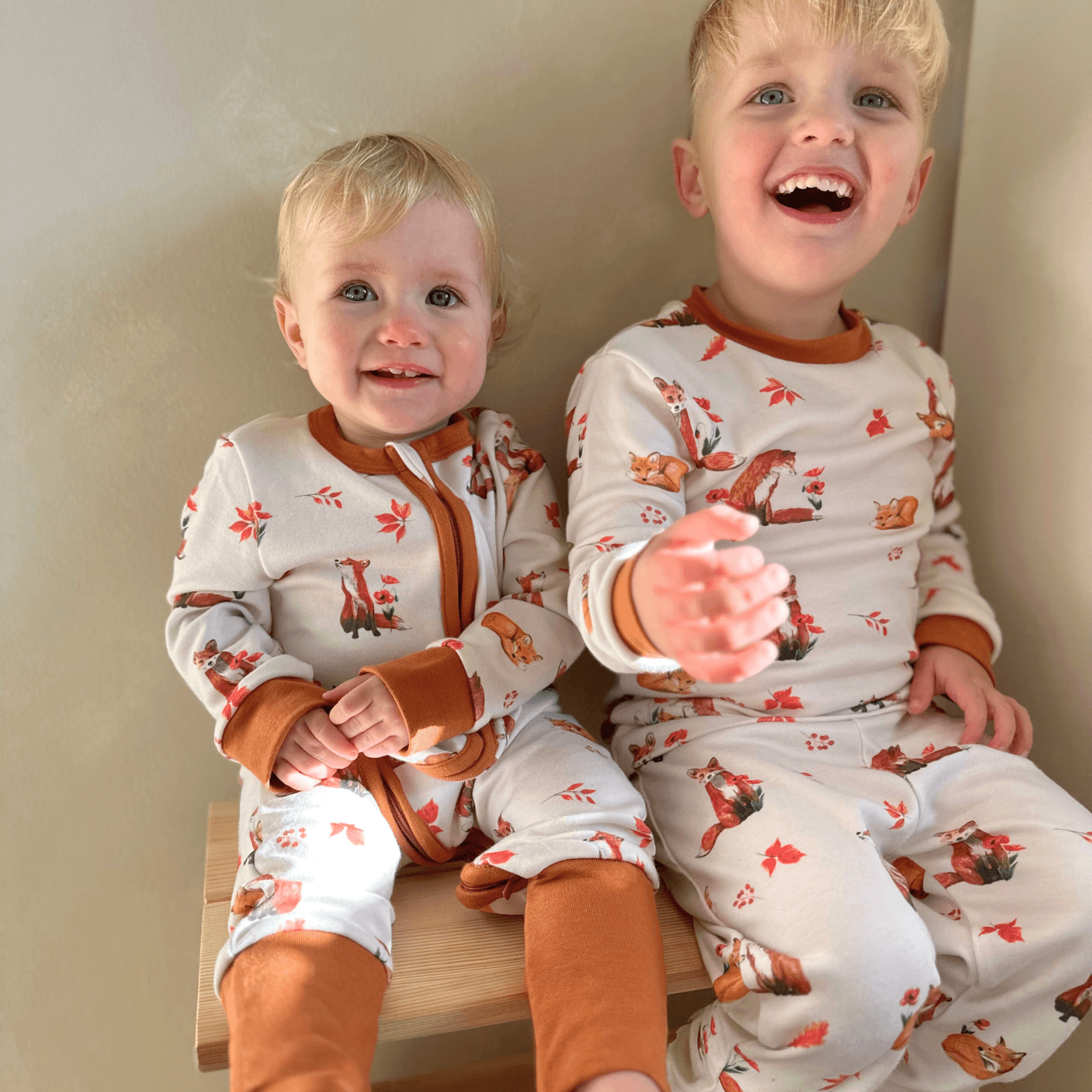 Smiling baby and toddler wearing matching Fluffy Foxes Sleepsuit with fox family print made from bamboo and organic cotton from GrowGrows