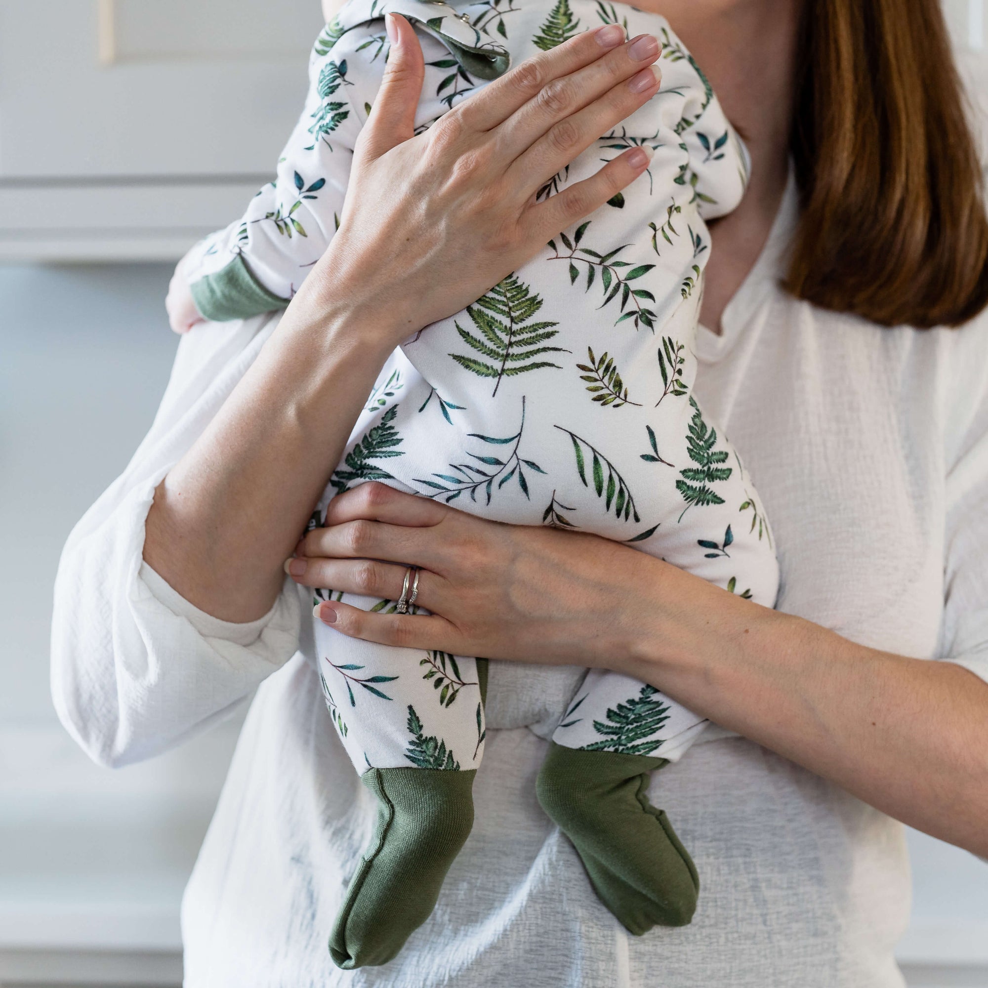 Close up of mum holding baby wearing the Country Leaf Sleepsuit with leaf print and integrated foldover socks from GrowGrows