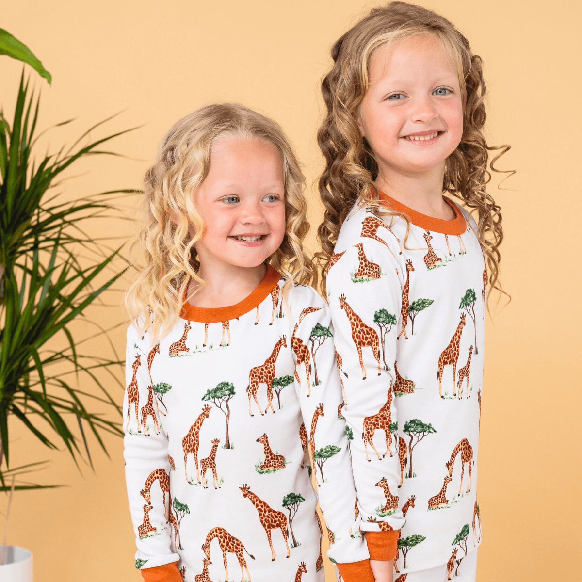 Two children wearing the Gentle Giraffes Pyjamas with giraffe print made from bamboo and organic cotton from GrowGrows