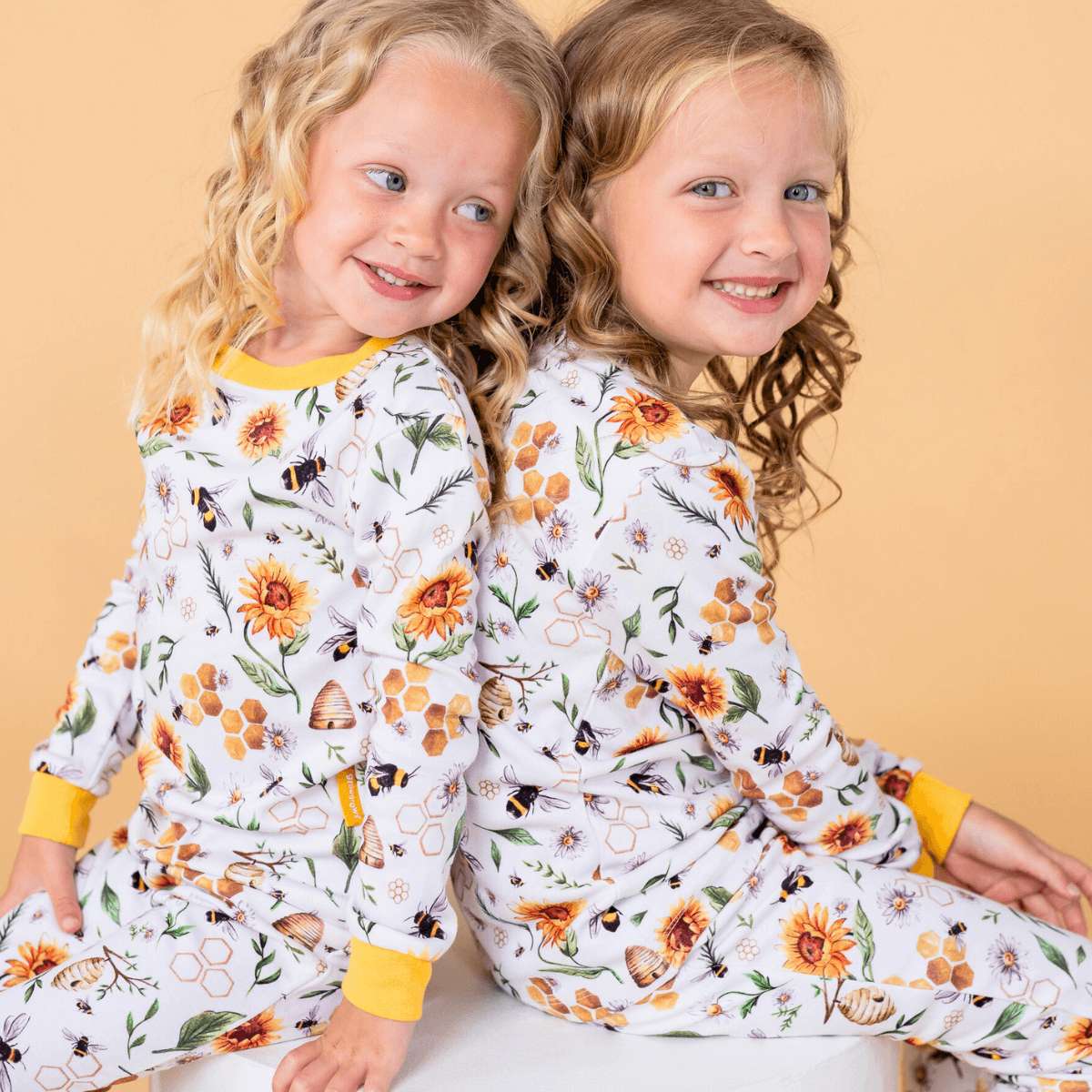 Two Children wearing the floral Honey Bees Pyjamas with bee print made from bamboo and organic cotton from GrowGrows