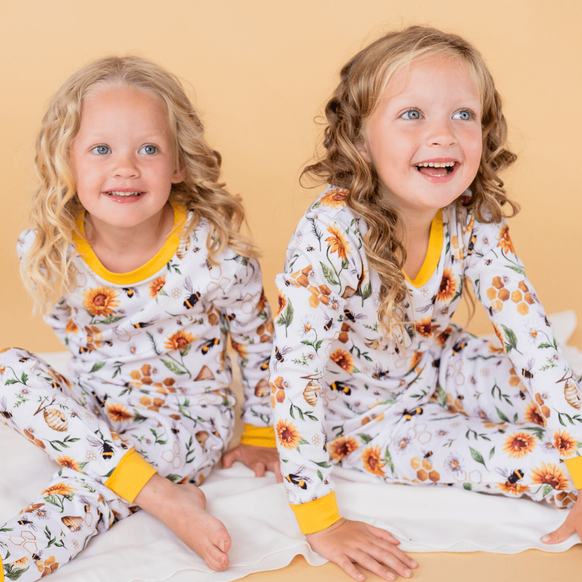 Two girls wearing matching Honey Bees Pyjamas with bee print made from bamboo and organic cotton from GrowGrows