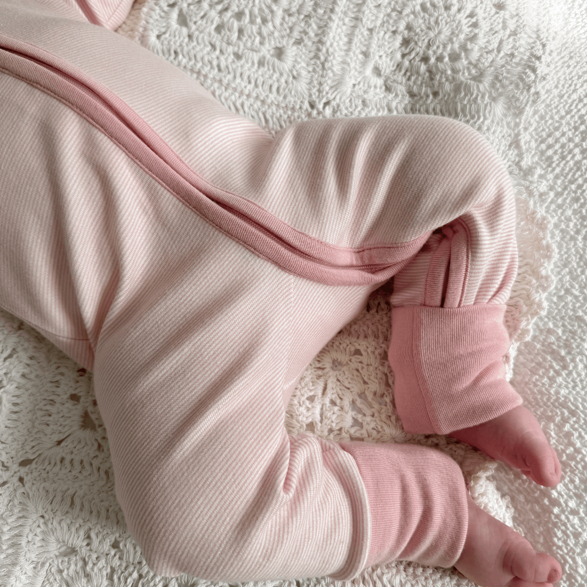 Close up of the folover socks and long 2-way zip on the Pink Pinstripe Sleepsuit with classic pink stripe design made from bamboo and organic cotton from GrowGrows