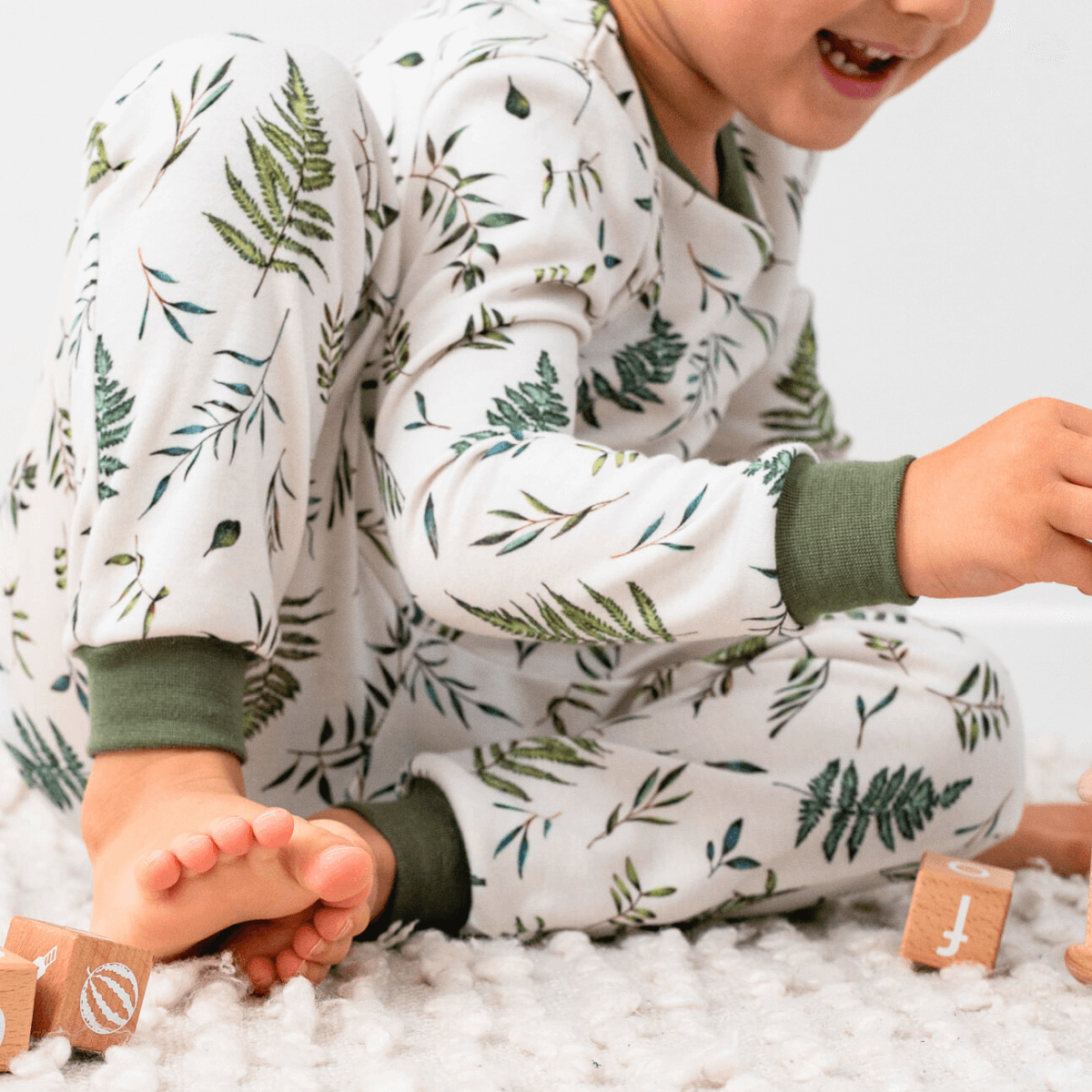 Close up of child wearing the Country Leaf Pyjamas with green botanical leaf print on a white background made from bamboo and organic cotton from GrowGrows