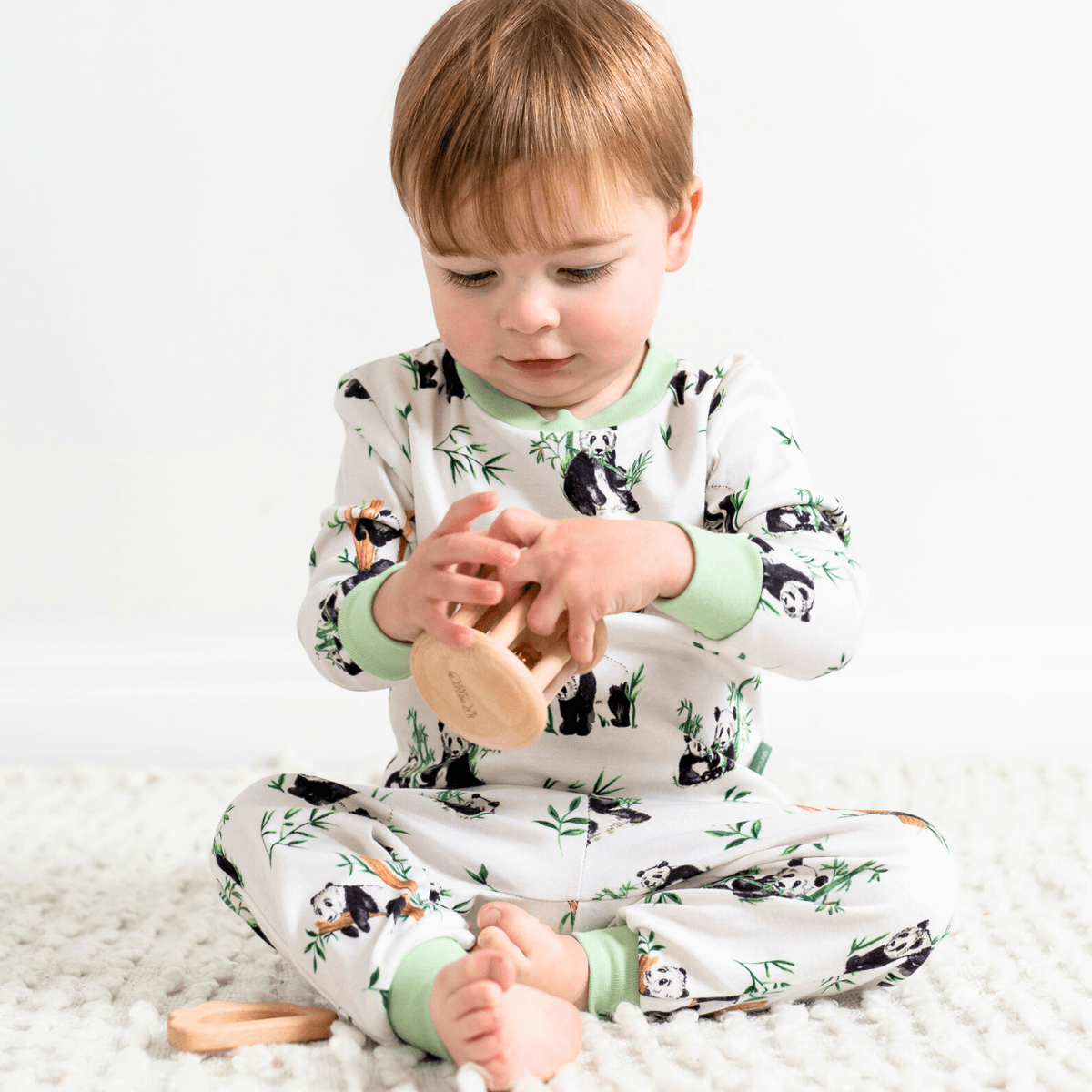 Child sat playing wearing the Playful Pandas Pyjamas with panda and bamboo print and sage green trim made from bamboo and organic cotton from GrowGrows