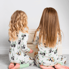two children sat playing on the floor wearing matching Playful Pandas Pyjamas with panda and bamboo print and sage green trim made from bamboo and organic cotton from GrowGrows