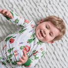 Toddler lying on the floor wearing the Alpine Adventures Pyjamas with chalet, fir tree and skier print and forest green trim made from bamboo and organic cotton from GrowGrows