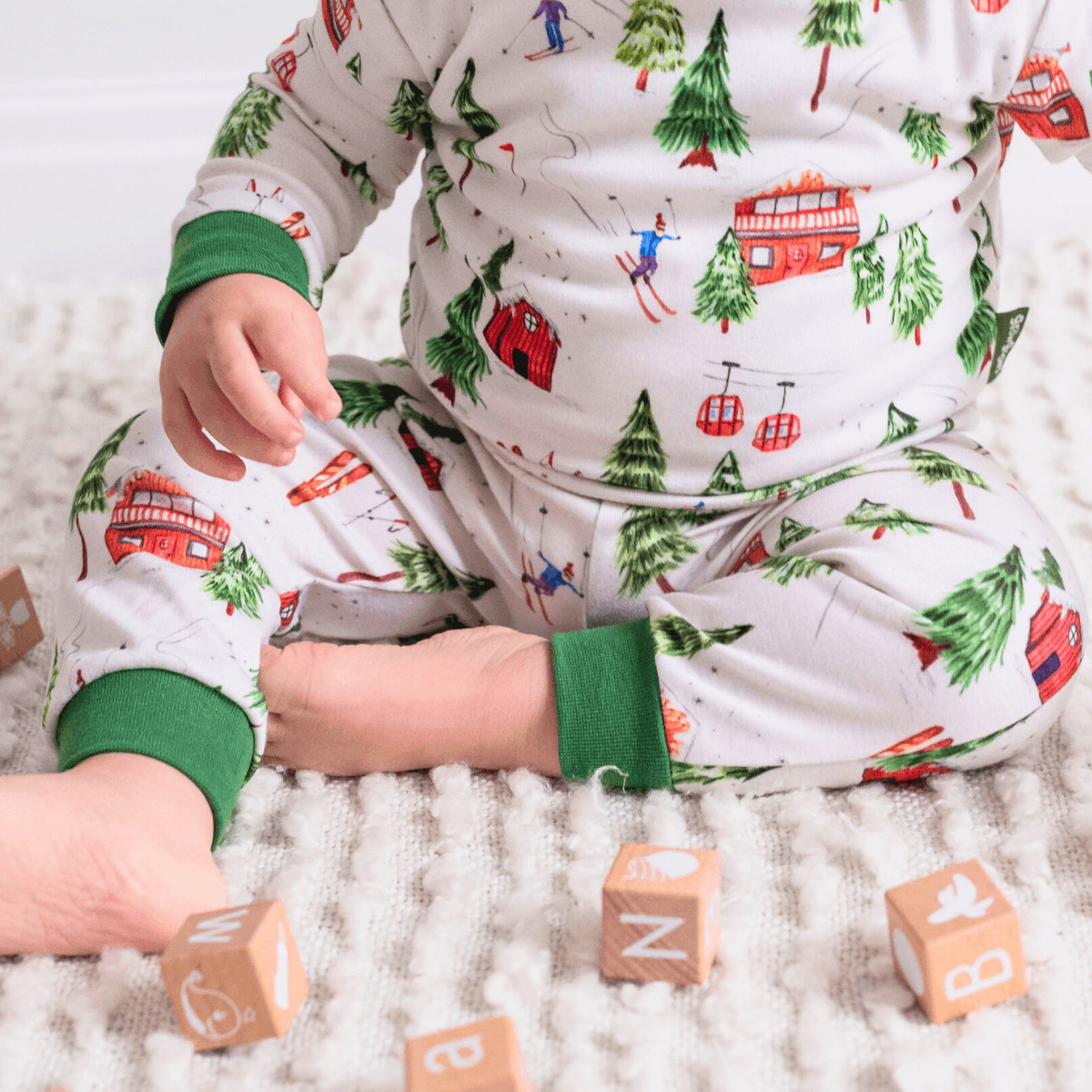 Close up on the cuffs of the Alpine Adventures Pyjamas with chalet, fir tree and skier print and forest green trim made from bamboo and organic cotton from GrowGrows