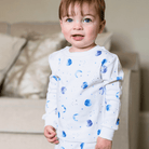 Child stood in the living room wearing the Marvellous Moons Pyjamas with blue moon, planet and constellation print made from bamboo and organic cotton from GrowGrows