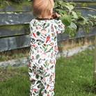 Childing standing outside in the garden wearing the Allotment Adventure Pyjamas with vegetable allotment print made from bamboo and organic cotton from GrowGrows