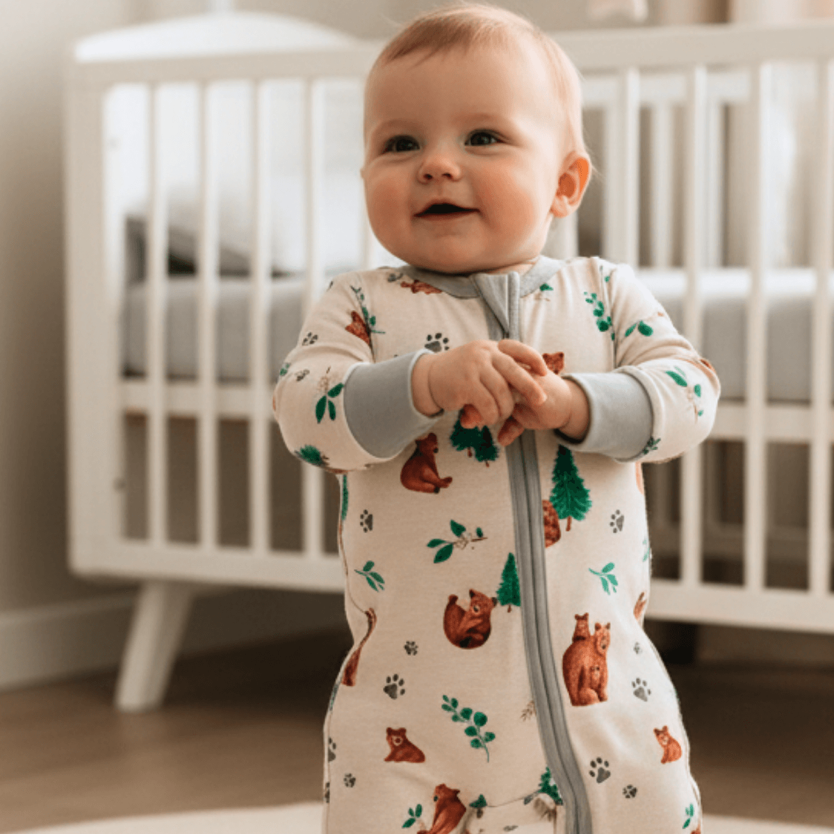 Baby stood in the nursery wearing the Cozy Cubs Sleepsuit with mama and cub bear print made from bamboo and organic cotton from GrowGrows