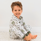 Child sat wearing the Country Leaf Pyjamas with green botanical leaf print on a white background made from bamboo and organic cotton from GrowGrows