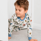 Child peeking around the door wearing the Dandy Dinos Pyjamas with dinosaur print made from bamboo and organic cotton from GrowGrows