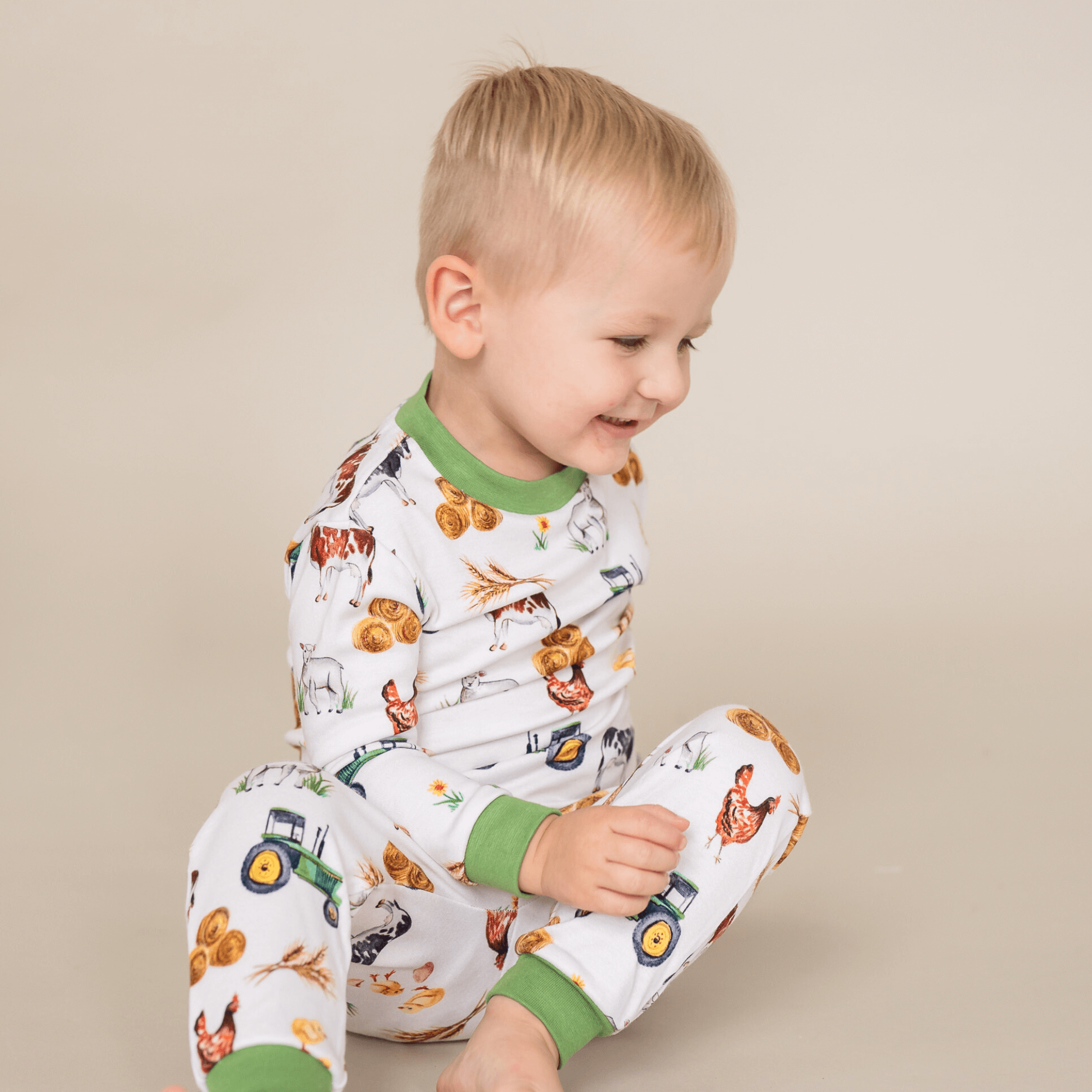 A young child wearing the Family Farm Pyjamas with farmyard animal and tractor print made from bamboo and organic cotton from GrowGrows