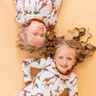 Two children wearing the Gentle Giraffes Pyjamas with giraffe print made from bamboo and organic cotton from GrowGrows