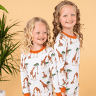 Two children wearing the Gentle Giraffes Pyjamas with giraffe print made from bamboo and organic cotton from GrowGrows