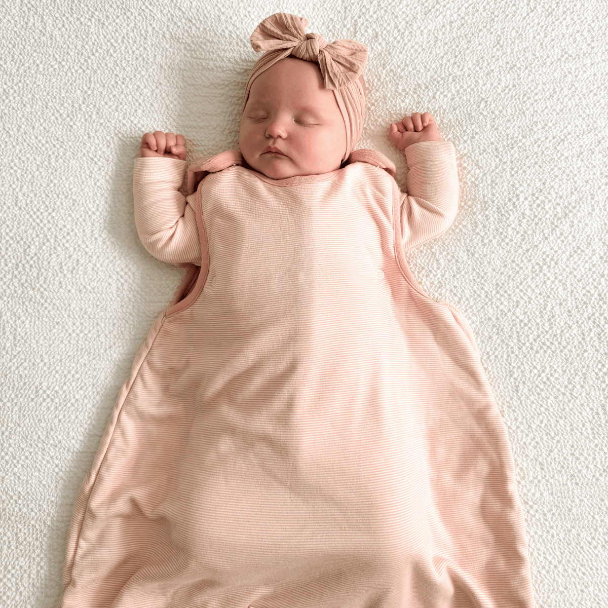 Newborn baby resting in the Pink Pinstripe Smart Sleeping Bag with pink pinstripe design made from bamboo and organic cotton from GrowGrows