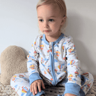 Toddler sat in bed wearing the Up, Up & Away Sleepsuit with hot air balloon and cloud print made from bamboo and organic cotton from GrowGrows