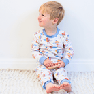 A child sitting on the floor wearing the Up, Up & Away Pyjamas with hot air balloon print made from bamboo and organic cotton from GrowGrows
