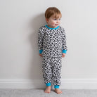 Boy stood against a white background wearing the Delightful Doodle Pyjamas with black and white doodle print and blue trim made from bamboo and organic cotton from GrowGrows